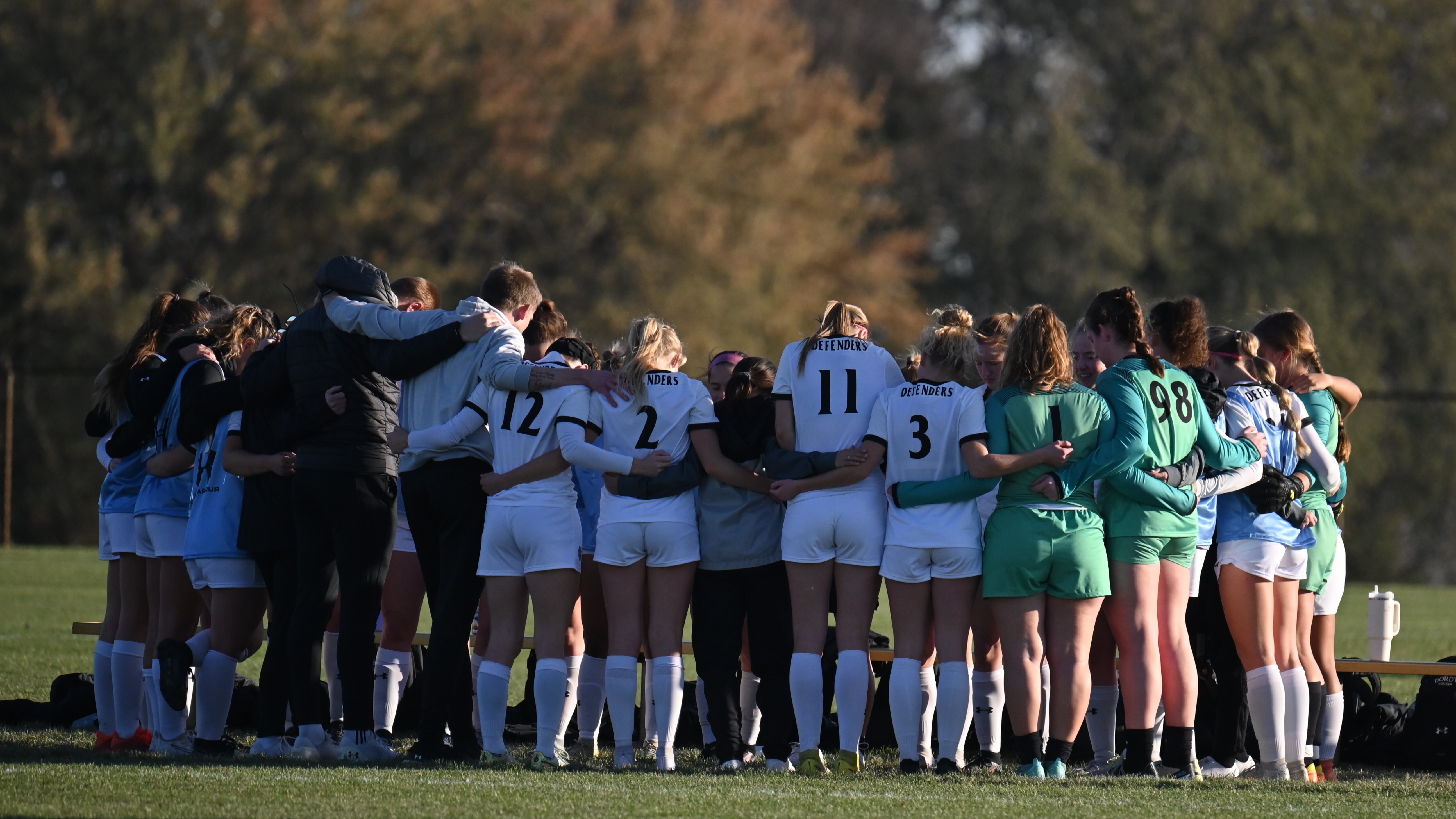 Female soccer players pray before game