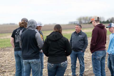A picture of a professor talking to students in a field
