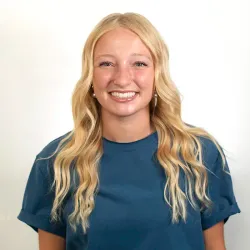 Young lady with blond hair and blue shirt smiles for camera