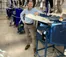 A picture of a man in a light blue shirt standing next to machinery