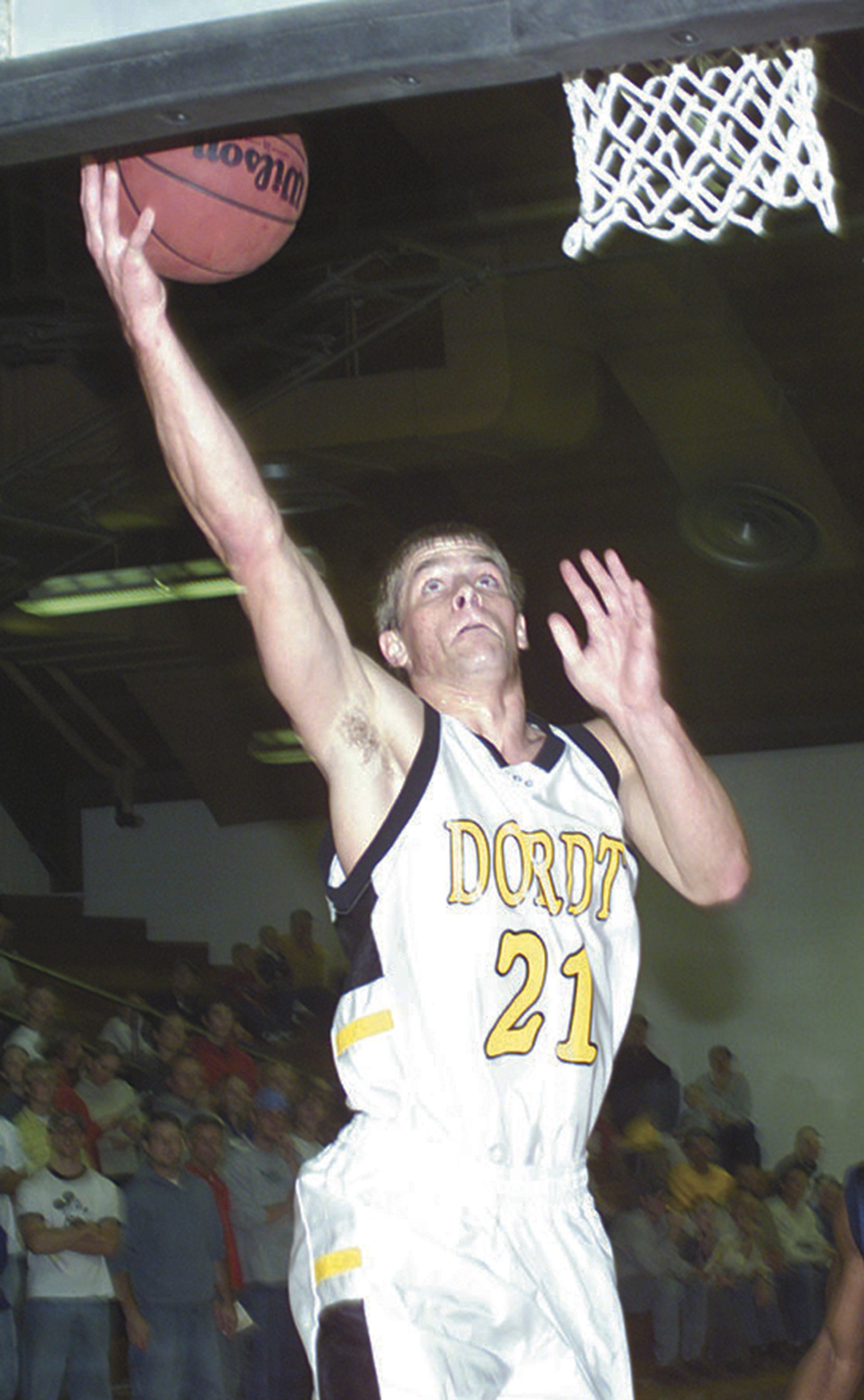 Old photo of young man playing basketball, going up for layup