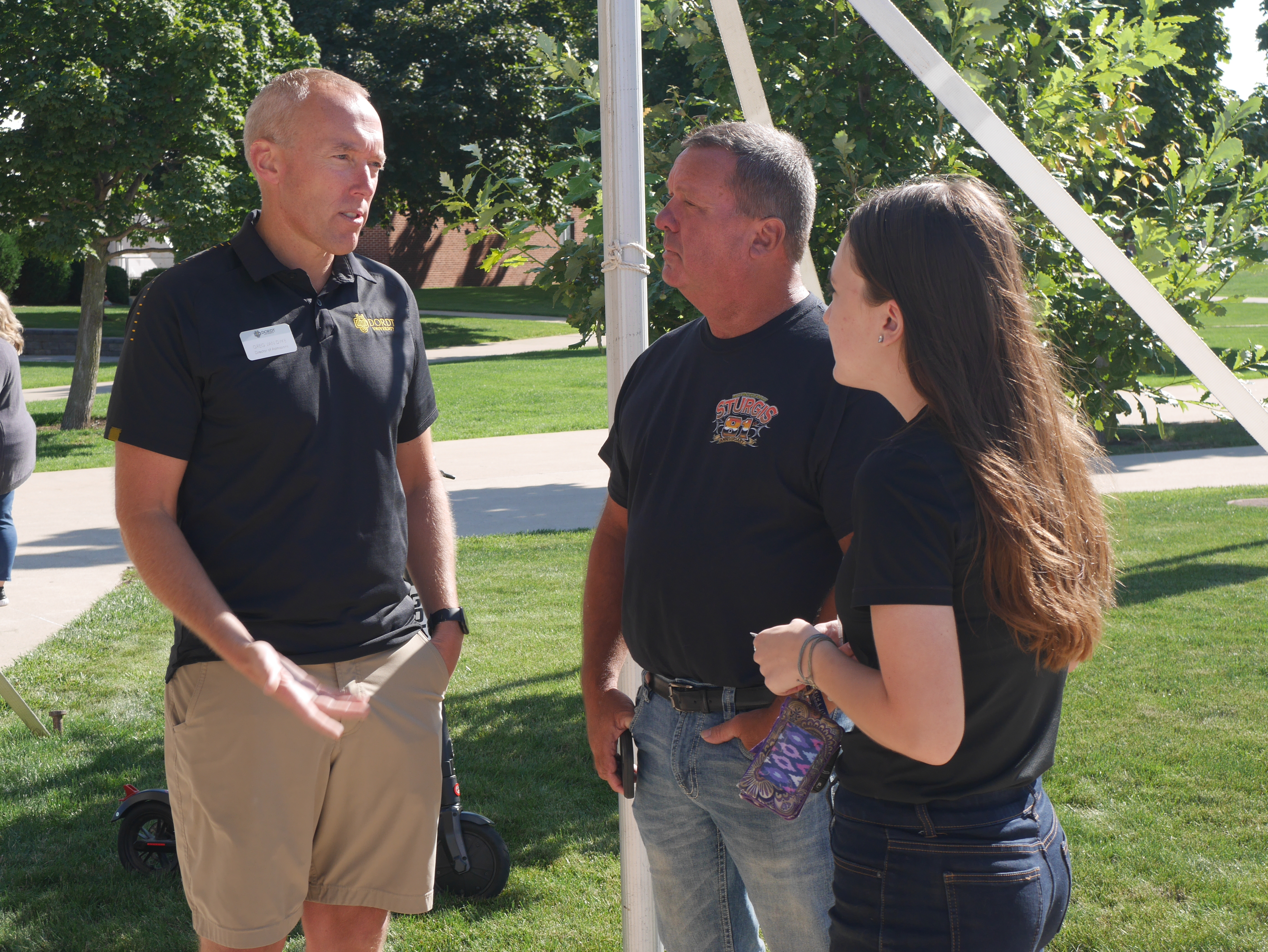 father and daughter talk with admissions counselor outside