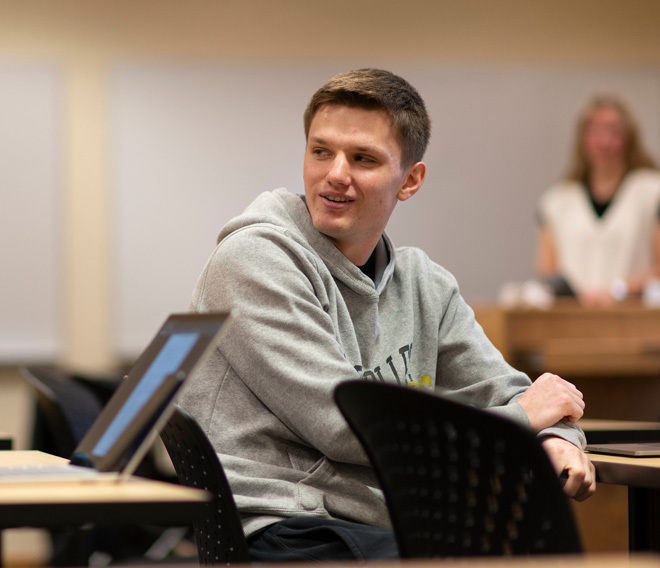 A Dordt student sitting at his desk looking back at his classmates