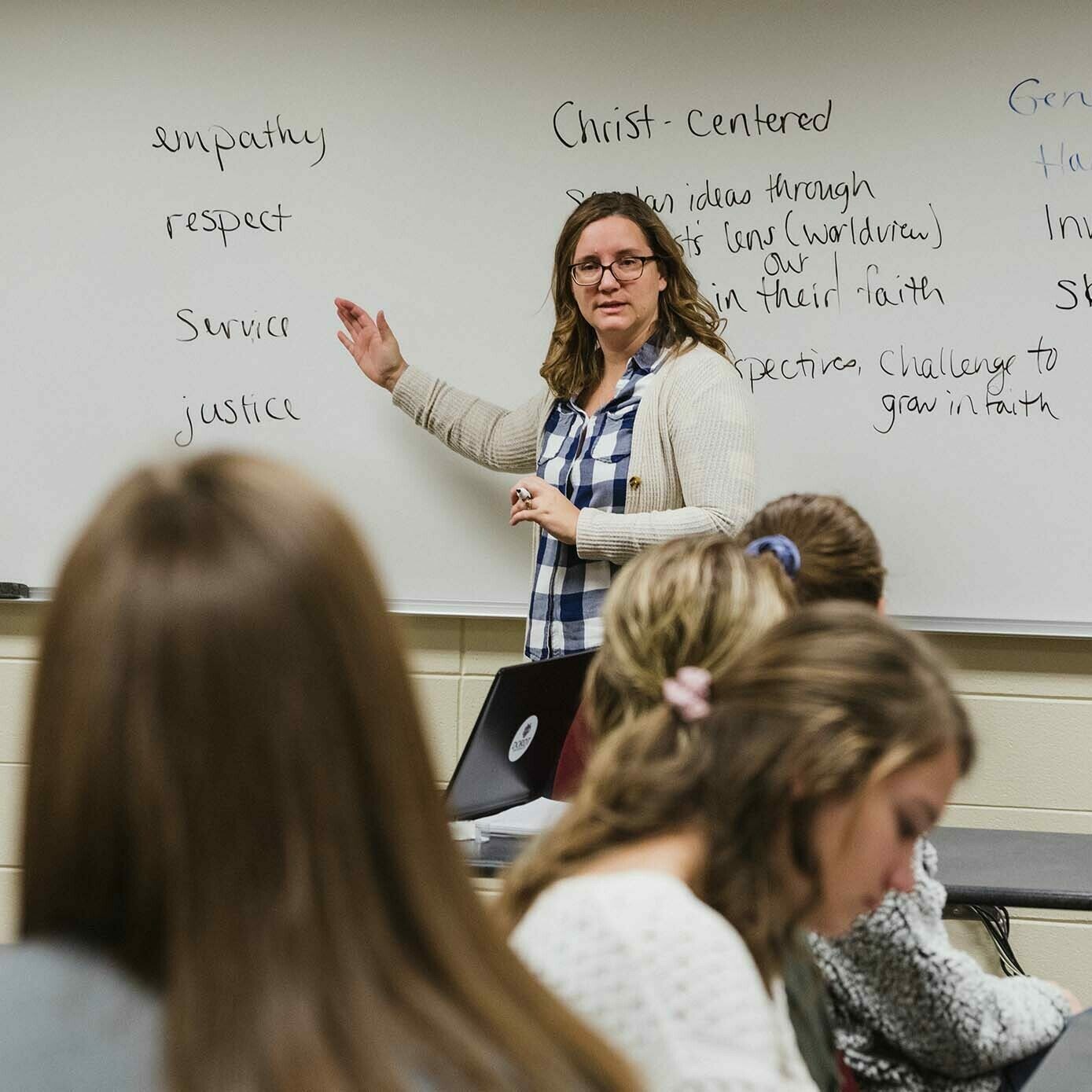 Social work professor points to writing on the board during a lecture