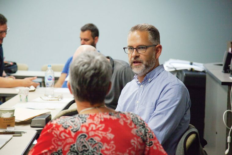 A picture of a man in a light blue shirt talking to a women in a red shirt