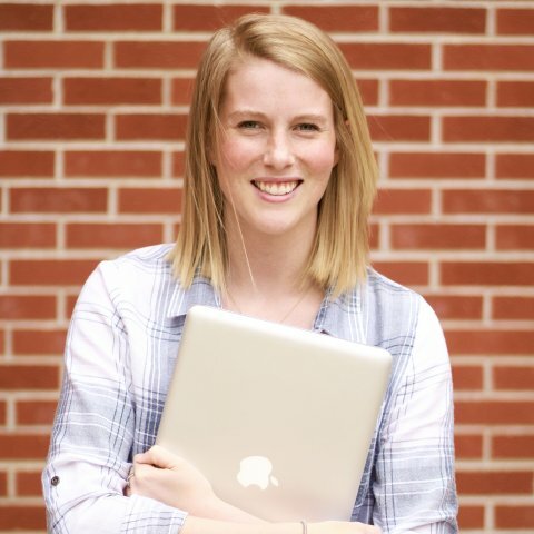 A picture of a women in a light blue shirt with holding a laptop