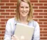 A picture of a women in a light blue shirt with holding a laptop