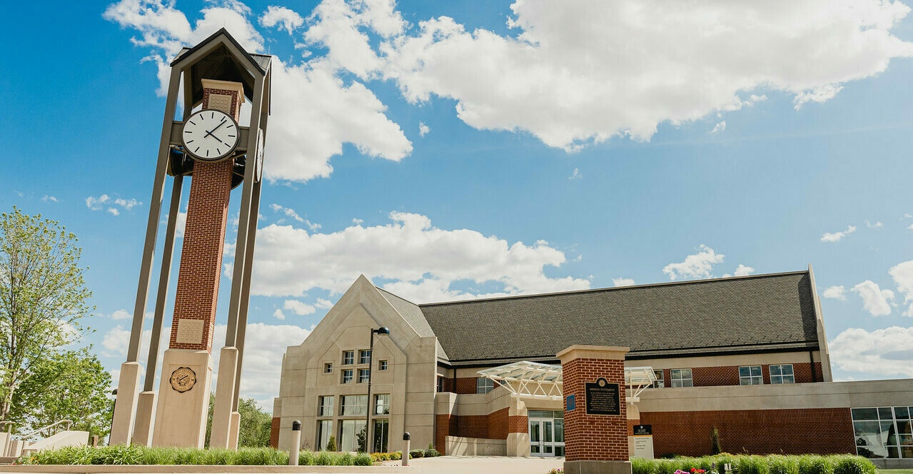 A picture of Dordt's clocktower and campus center on a sunny day with big white clouds in the background.