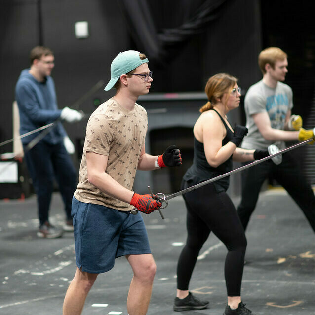 theatre arts students pretend to fight with fake swords