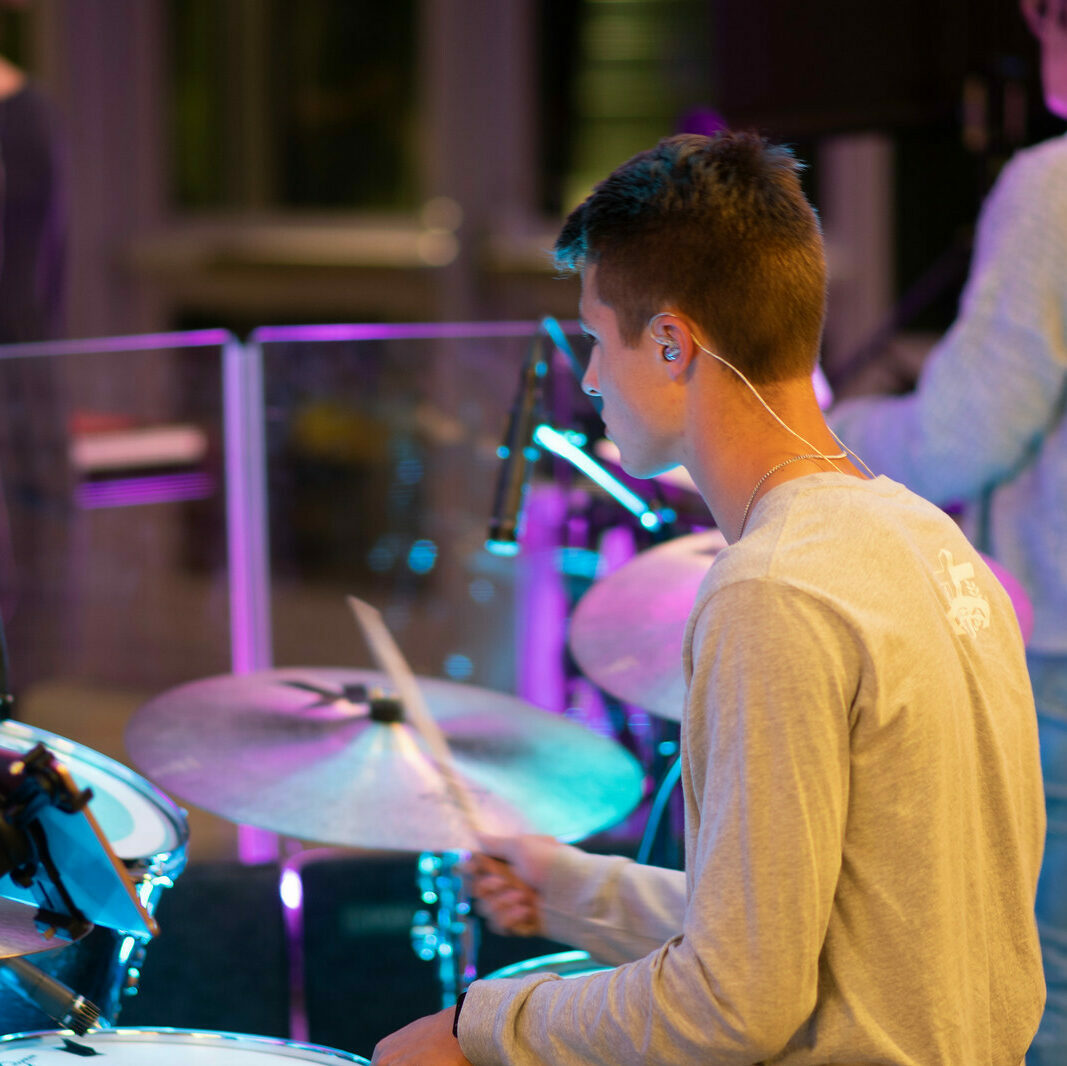 male student plays the drums during praise and worship