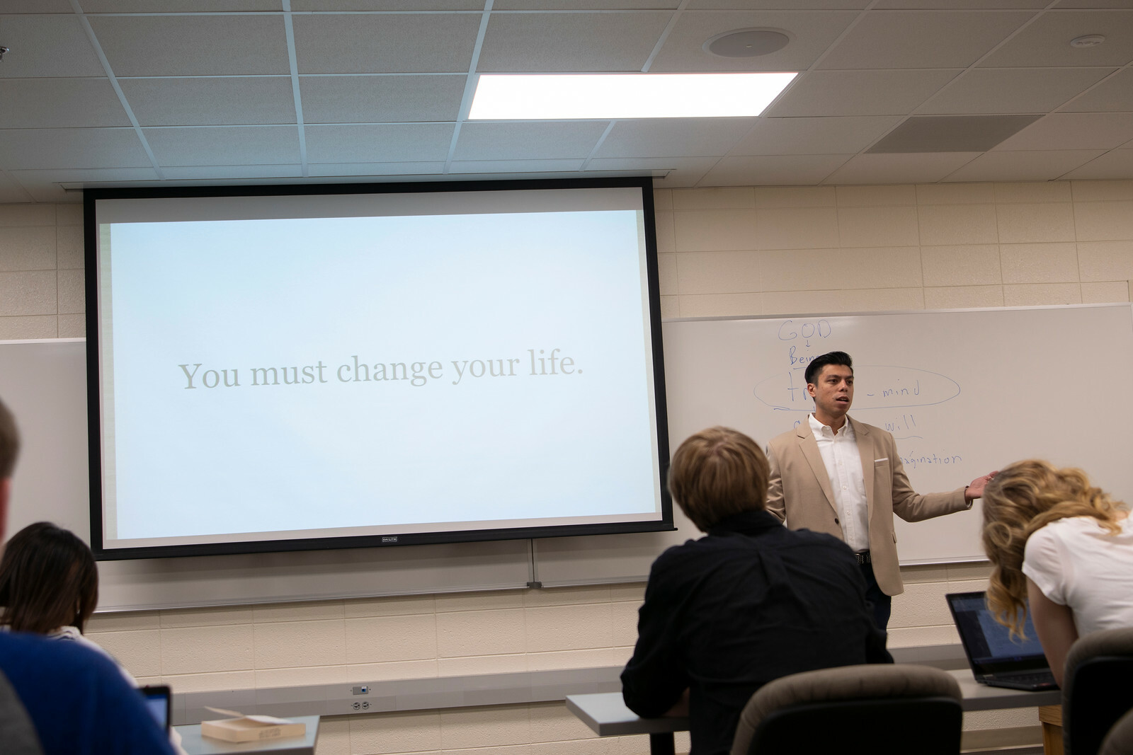 Dr. Justin Bailey presents a PowerPoint and lectures in front of the class