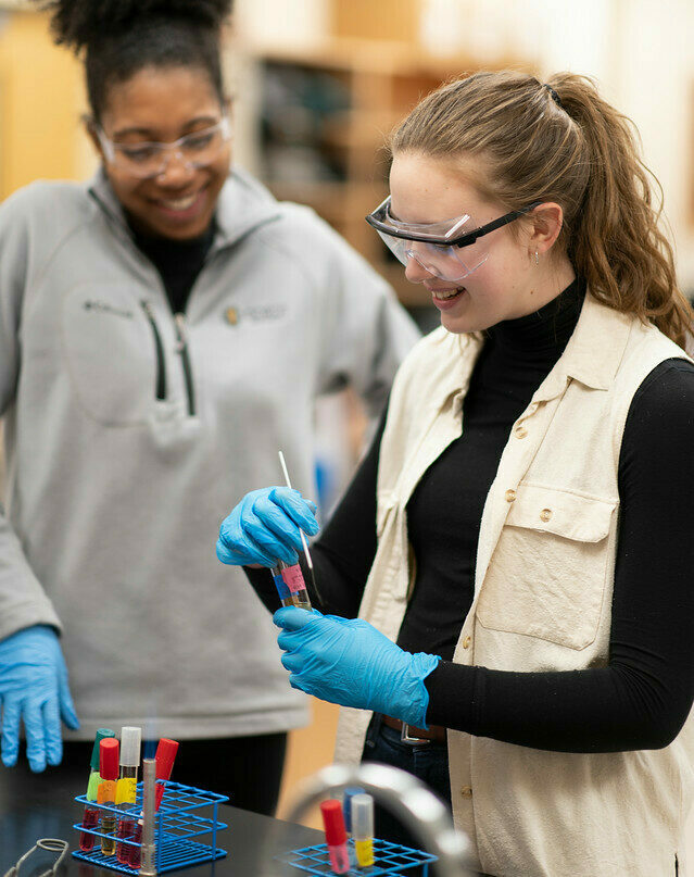 students examine glass vile during lab