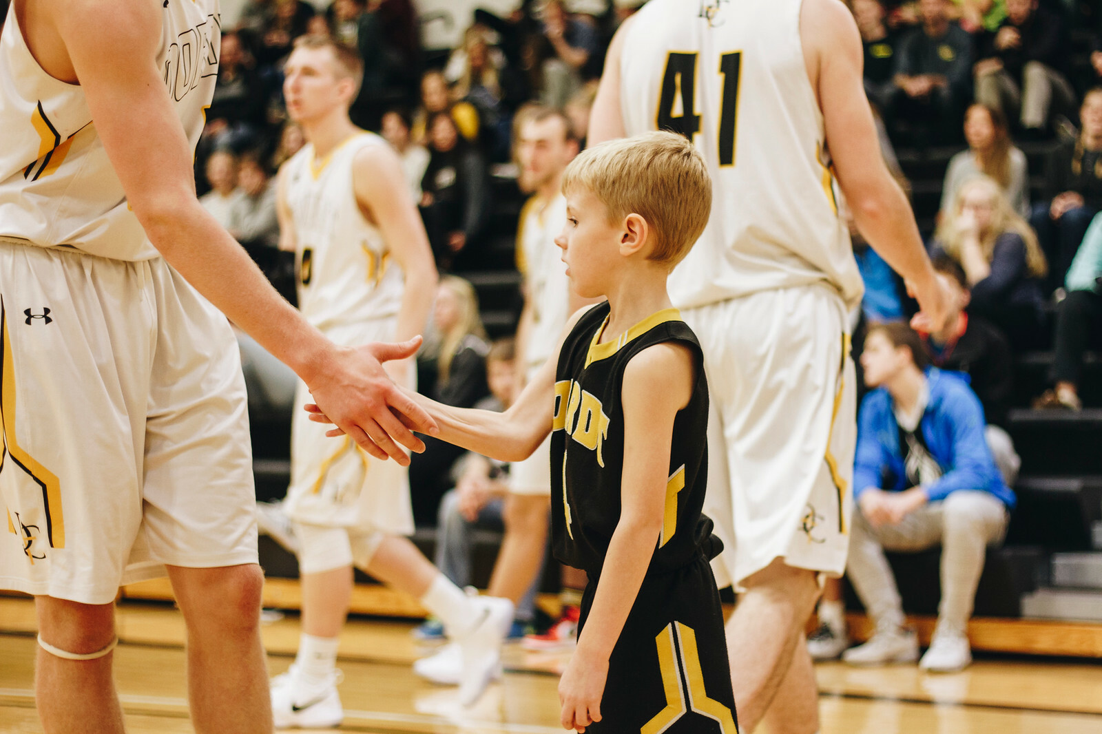 A child shakes a basketball player's hand