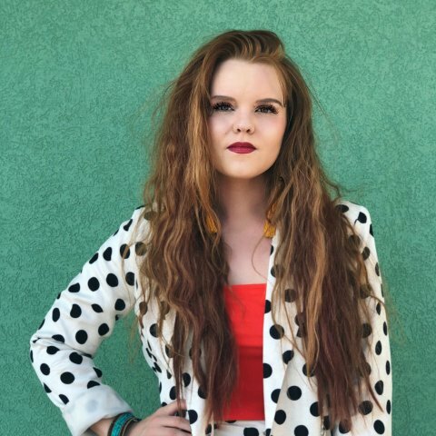 A picture of a women wearing a black and white polka-dot jacket with long brown hair