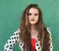 A picture of a women wearing a black and white polka-dot jacket with long brown hair