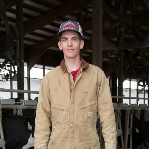 A picture of a man in a brown work jacket with a baseball cap