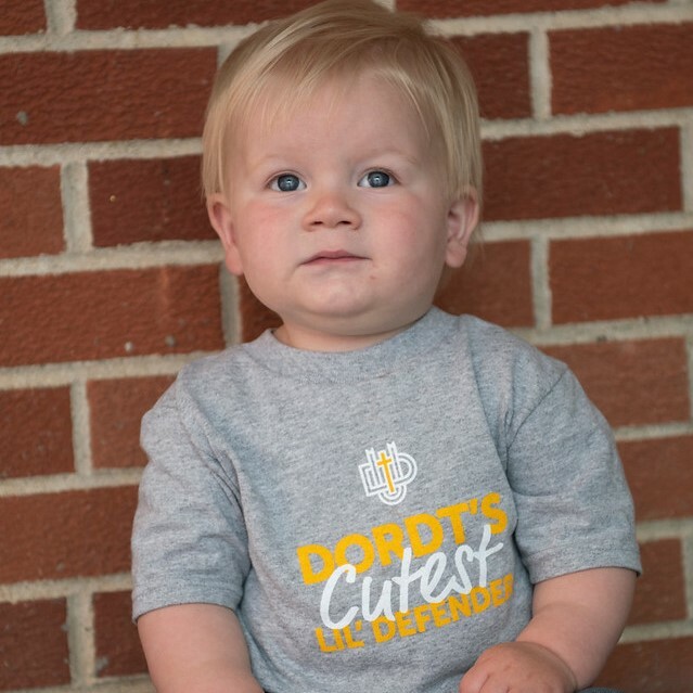 A picture of a child wearing a "Dordt's cutest lil' Defender" shirt